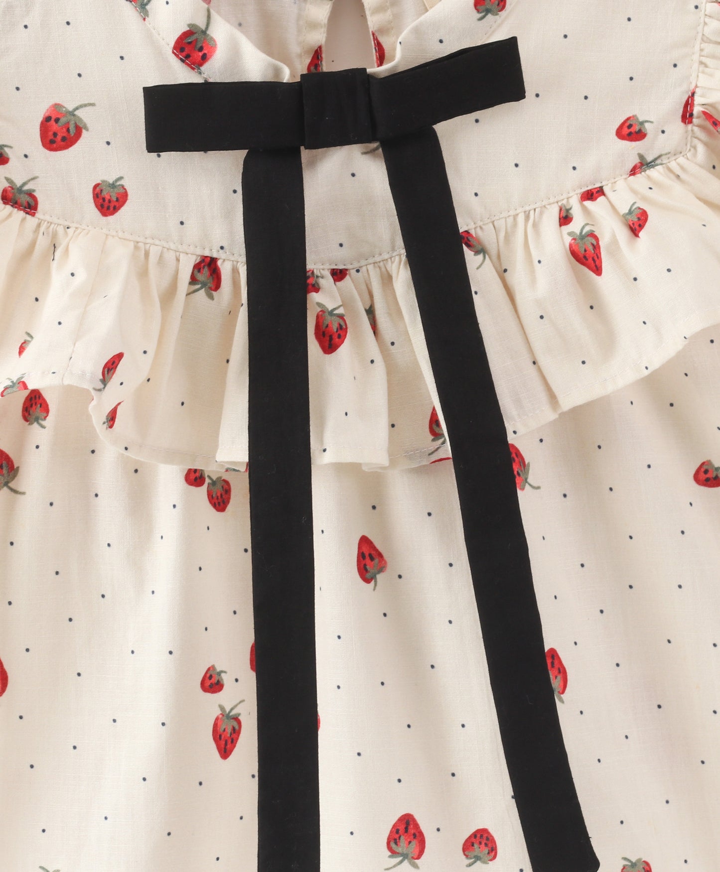 White top with strawberry and dot print with black bow tie at neck