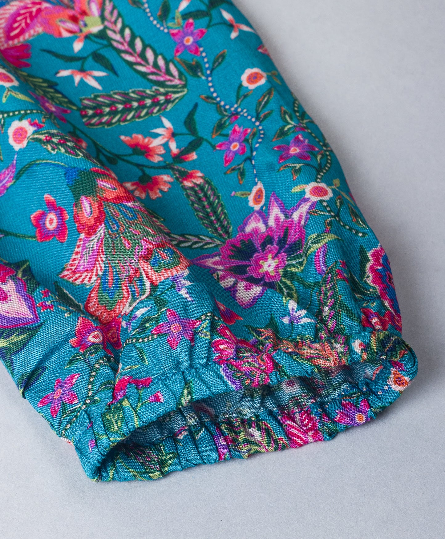 TURQ AND PURPLE FLORAL PRINT TOP WITH FRILLS ON THE FRONT SIDES
